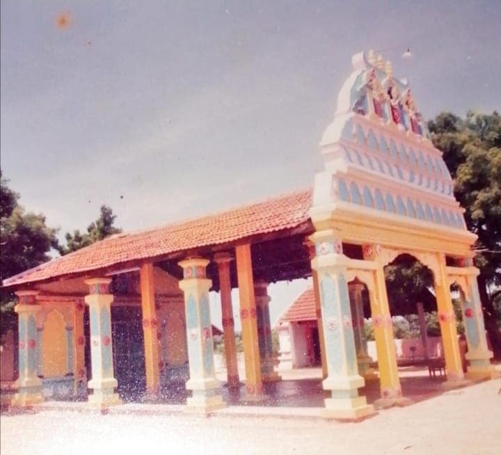 A temple mandapam and tower, with a tiled roof and painted pillars
